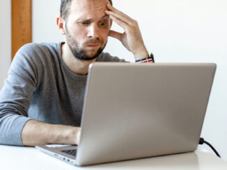 young man looking puzzled working at laptop